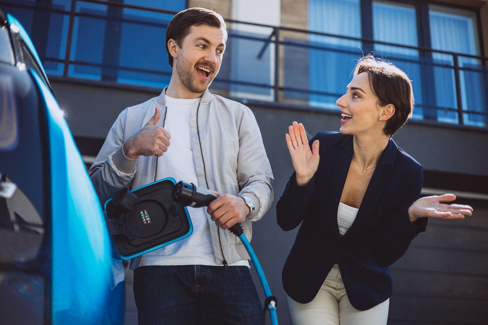 Enthusiastic couple beside a charging electric car